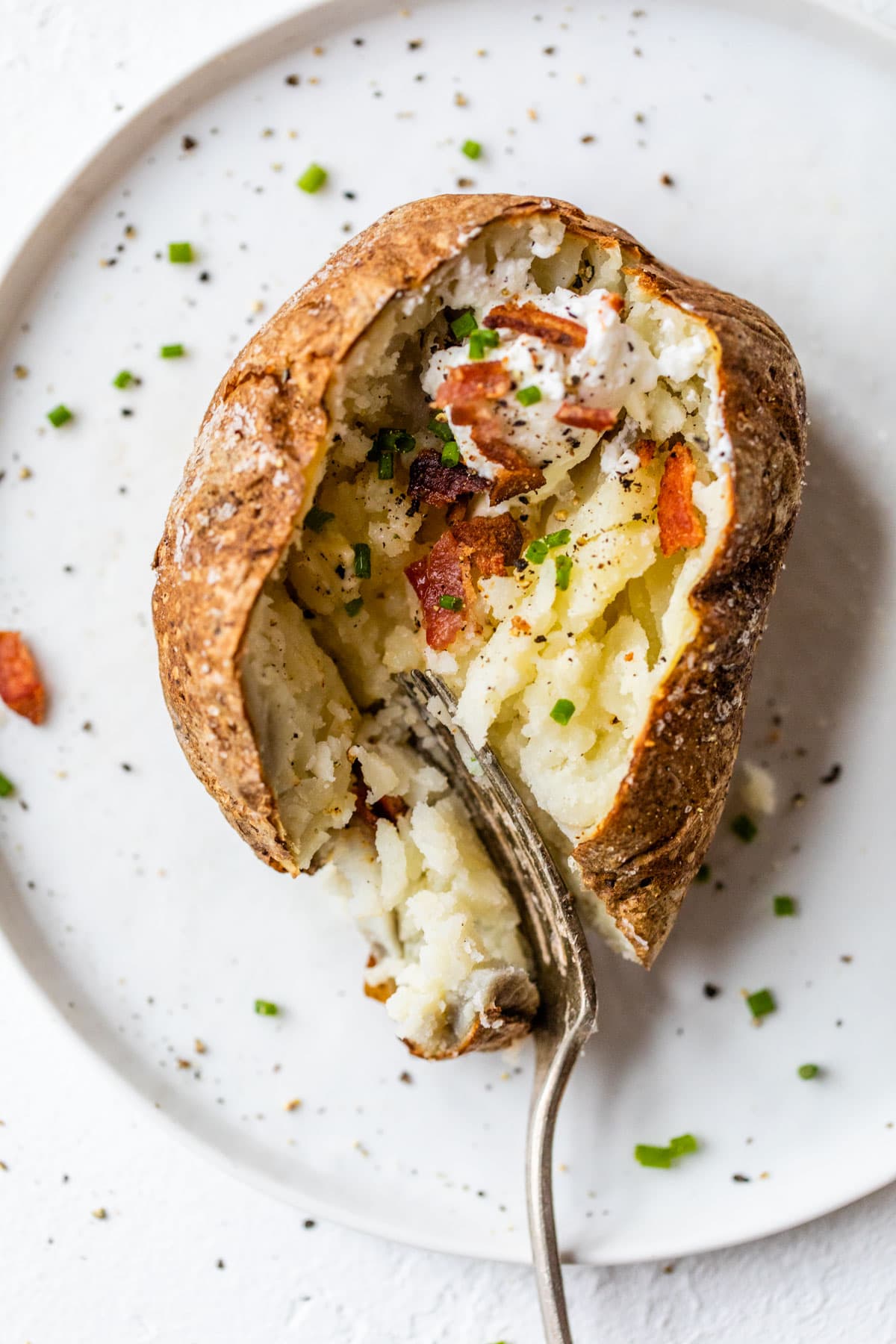 A fork cutting into an air fryer baked potato