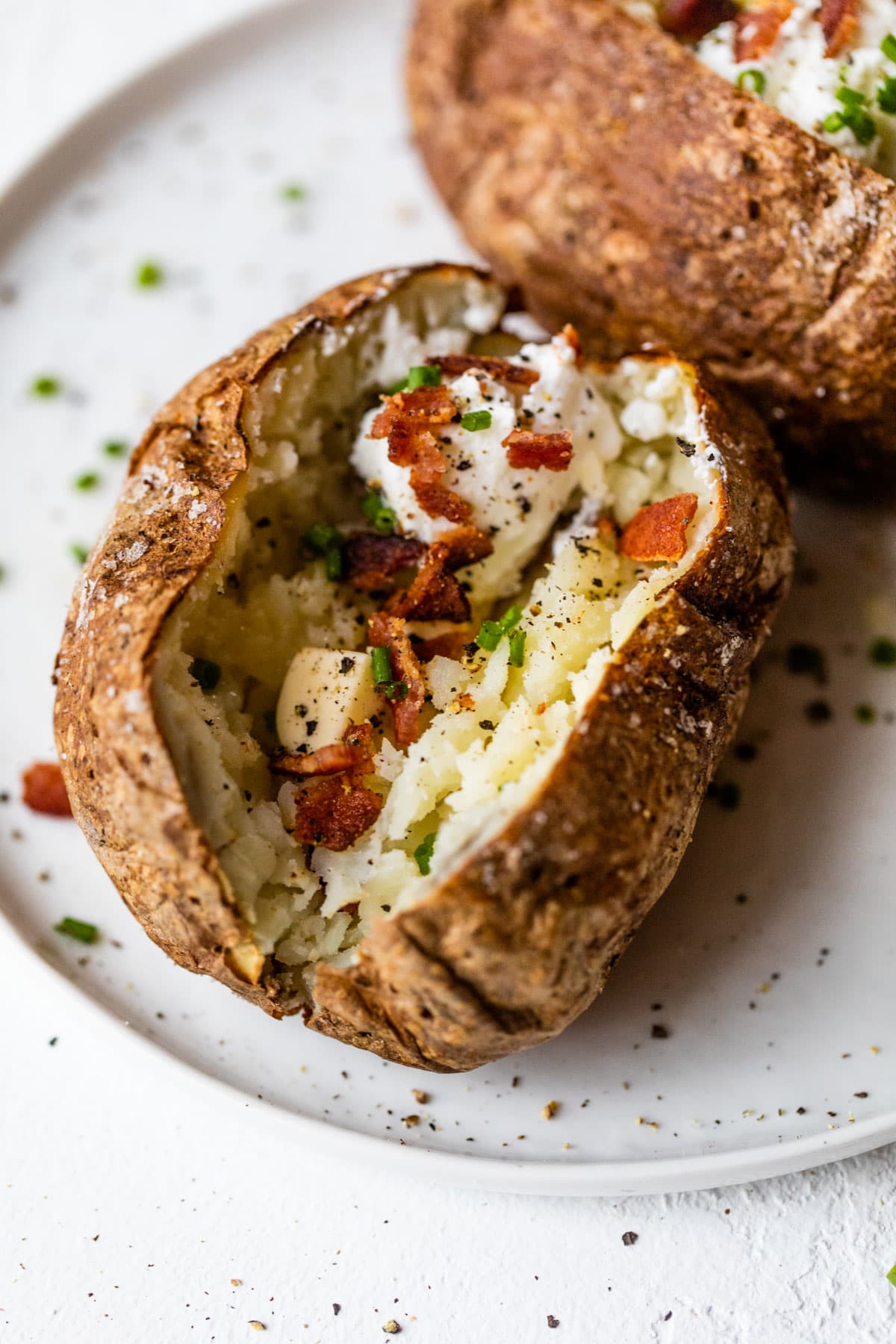 An air fryer baked potato with butter and bacon